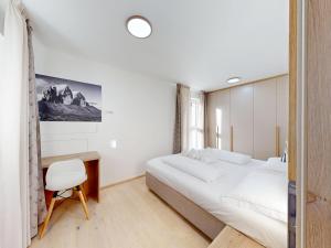 a bedroom with a large white bed and a desk at Aurturist Dobbiaco Roulette in Dobbiaco