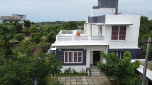 a white house with a balcony on a hill at Manoj hotel in in Covelong