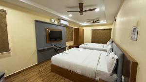 ein Hotelzimmer mit zwei Betten und einem Flachbildfernseher in der Unterkunft Lakshmi Narayana Grand in Kanchipuram + 25 Fotos