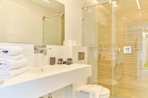 um banheiro branco com pia e chuveiro em H7 TLV em Tel Aviv mais 54 fotografias