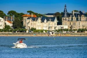 ein Boot im Wasser vor einer Stadt in der Unterkunft L'Oranger bleu in Royan