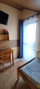 ein Schlafzimmer mit einem Bett und einem Tisch und einem Fenster in der Unterkunft Pokoje Gościnne VEIKSME in Bestwina