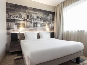 1 dormitorio con 1 cama blanca y una imagen en blanco y negro en Novotel Duesseldorf Airport, en Düsseldorf