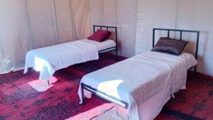 two beds in a room with white sheets at Iriki Desert Camp Foum Zguid in Bou Guir