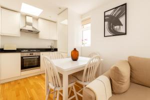 a kitchen and living room with a white table and chairs at Superb 2 Bed Apartment in Battersea in London