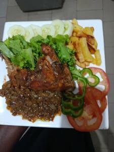 NiodiorGîte Daline Guenaar的盘子上的食物,包括肉、蔬菜和薯条