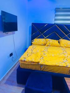 Un dormitorio con una cama con sábanas amarillas y un televisor. en T Apartment, en Ogijo