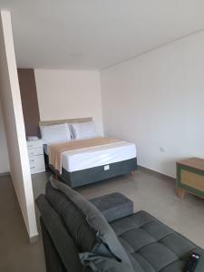 een slaapkamer met een bed en een bank bij studio 11 em Praia de Leste beach 1quarto in Pontal do Paraná