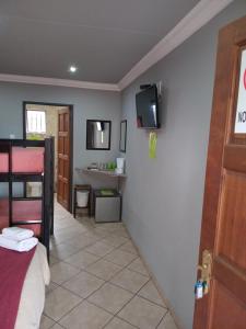 a room with a bed and a bathroom with a sink at Grand Central Guesthouse in Rustenburg