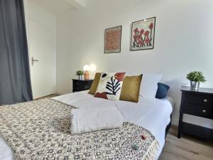 une chambre avec un lit avec des draps blancs et des oreillers dans l'établissement Le Cornas, à Tournon-sur-Rhône