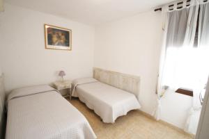 Una habitación blanca con dos camas y una ventana. en Casa Becker, en Miami Platja