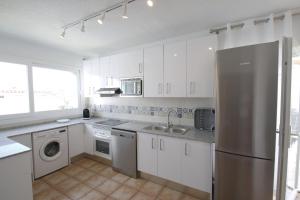 a kitchen with white cabinets and a stainless steel refrigerator at Villa Atenea in Miami Platja