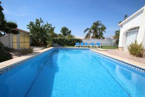 a swimming pool with two blue chairs and a house at Villa Atenea in Miami Platja
