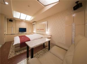 a bedroom with a bed and a couch and a table at Prime Hotel Fulula プライムホテル フルーラ in Osaka