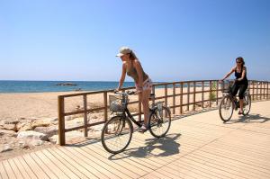 two women riding bikes on a boardwalk near the beach at Villa rustical 14 in Montroig