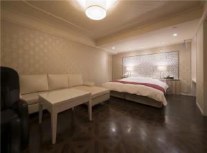 a bedroom with a bed and a couch and a table at Prime Hotel Fulula プライムホテル フルーラ in Osaka