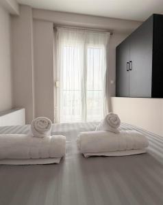 ein weißes Zimmer mit zwei Betten und einem Fenster in der Unterkunft Panorama Sunvilles Apartment 6 in Thessaloniki