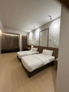 Dos camas en una habitación de hotel con pájaros en la pared en Windmill Upon Hills Genting Highland by El Naura, en Genting Highlands