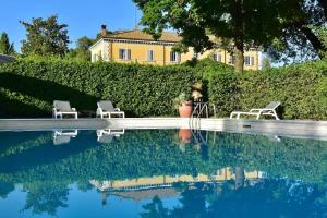 a pool with two chairs and a house in the background at Country Loft at Palazzo di Bagnaia in Castel del Piano