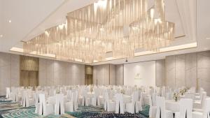a conference room with white chairs and a large chandelier at Holiday Inn Lampung Bukit Randu by IHG in Bandar Lampung +128 photos