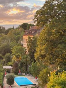 a swimming pool in front of a house and a building at Les Hauts de Domme - Chambres d'hôtes in Domme