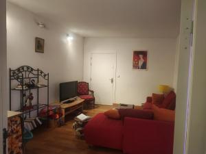 a living room with a red couch and a tv at Au P'tit Venton - Maison Écologique in La Jaille-Yvon