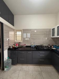 eine große Küche mit schwarzen Schränken und einer Arbeitsplatte in der Unterkunft Just for womens homestay in Chikmagalur
