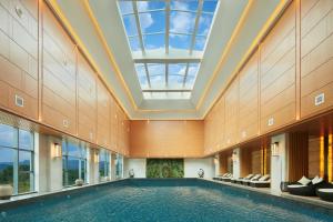 a pool in a building with a skylight at New Century Grand Hotel Zunyi in Zunyi