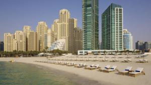 einen Strand mit Liegen, Stühlen und Gebäuden in der Unterkunft Al Bateen · Ultra Luxury JBR · Private Beach and Pool in Dubai