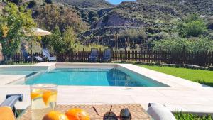 a swimming pool with a table with oranges and a drink at Tropical Studio in Órgiva