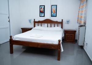 ein Schlafzimmer mit einem Holzbett mit weißer Bettwäsche in der Unterkunft El Hotelito in San José