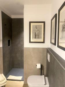 ein Badezimmer mit Toilette und Bildern an der Wand in der Unterkunft Independent Room in Villa with Pool in Costermano sul garda