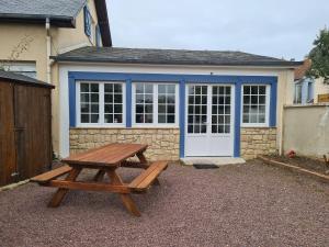 a wooden picnic table in front of a house at Cottage Le pêcheur du Grand Large proximité plage in Asnelles