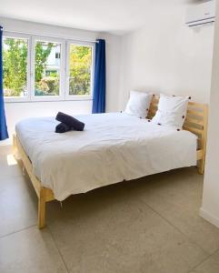 1 Schlafzimmer mit einem großen Bett mit weißer Bettwäsche und 2 Fenstern in der Unterkunft La Cabanne, 4 people, Royan center, 50 m beach, air conditioning in Royan