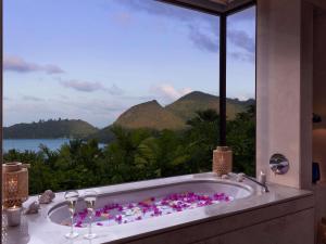 ein Bad mit einer Badewanne und Meerblick in der Unterkunft Raffles Seychelles in Baie Sainte Anne