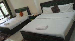 a bedroom with two beds with white sheets and pillows at Kempty Lake Waterfall Resort - Run by Anaysha Group in Mussoorie