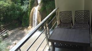 a balcony with two chairs and a view of a waterfall at Kempty Lake Waterfall Resort - Run by Anaysha Group in Mussoorie