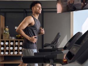 un hombre corriendo en una cinta de correr en un gimnasio en ibis Styles Dubai Deira, en Dubái
