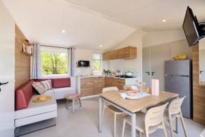 a kitchen and living room with a table and a couch at Camping de la Tour AMBON in Ambon