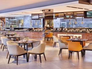 ein Restaurant mit Tischen und Stühlen und eine Bar in der Unterkunft Grand Mercure Bali Seminyak in Seminyak