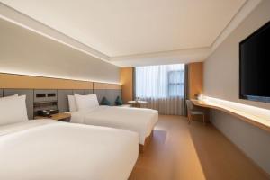 ein Hotelzimmer mit zwei Betten und einem Flachbildfernseher in der Unterkunft All Seasons Hotel Guangzhou Wuyangcun Metro Station in Guangzhou