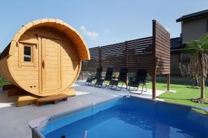 a round wooden sauna next to a swimming pool at 糸島リトリートヴィラ芥屋 in Itoshima