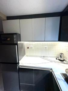 una cucina con mobili bianchi e un frigorifero nero di Luxe Apartments Surulere a Lagos