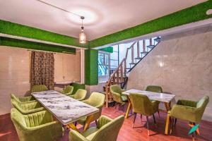 a restaurant with green walls and tables and chairs at Zostel Homes Shoghi, Shimla in Shogi