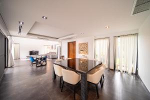 une salle à manger et un salon avec une table et des chaises dans l'établissement BangTao 3 Bedroom 15m Super Large Pool Garden Villa Tropical Light Luxury Villa Super Large Private Space, à Ban Nong Chaeng