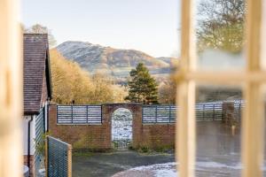 Ein Backsteingebäude mit einem Tor, im Hintergrund ein Berg in der Unterkunft Tiger Hall in Church Stretton