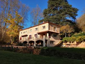 a large stone building with a tree in the background at Moulin les Forges gîte 12 places avec piscine chauffée en Périgord in Gavaudun