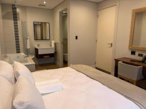 une chambre avec un grand lit blanc et une salle de bain dans l'établissement Umhlanga Apart Hotel, à Durban 12 autres photos