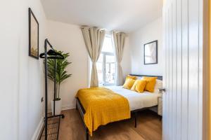 a bedroom with a bed with yellow pillows and a window at Open Mind Property - 4 BR, Hot Tub & Free Parking in Portsmouth