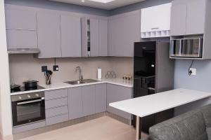 eine Küche mit weißen Schränken und einem schwarzen Kühlschrank in der Unterkunft Waterfront Apartment in Lüderitz